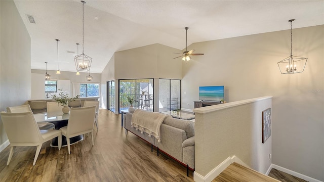 living room with hardwood / wood-style floors, ceiling fan with notable chandelier, and vaulted ceiling