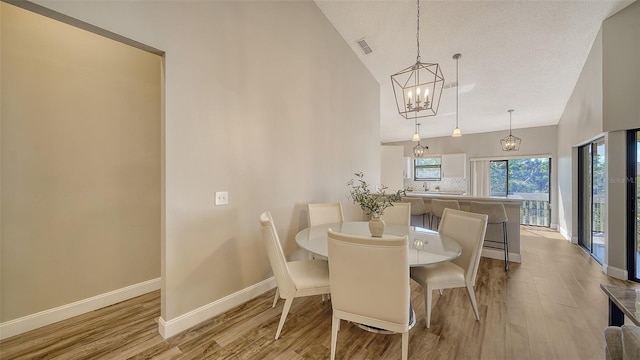 dining area featuring lofted ceiling, light hardwood / wood-style floors, and an inviting chandelier