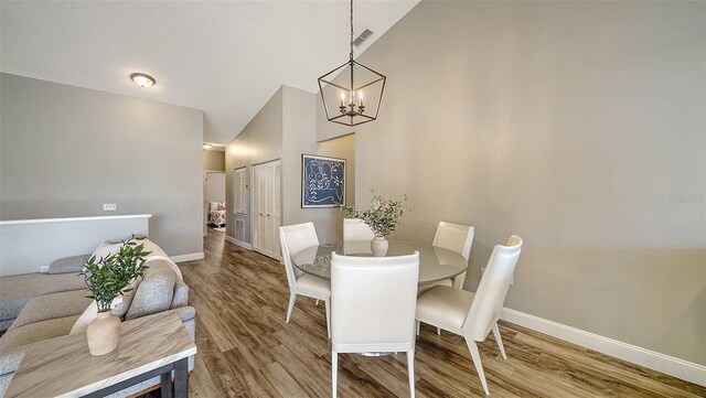 dining room featuring lofted ceiling, hardwood / wood-style flooring, and a chandelier