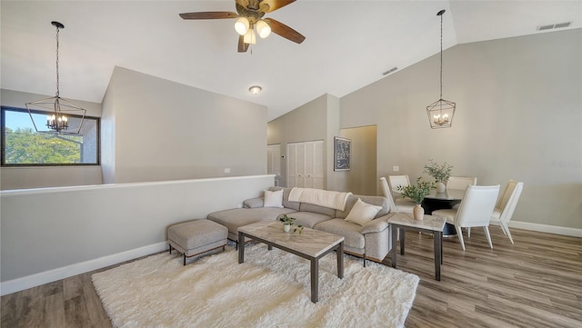 living room with lofted ceiling, hardwood / wood-style flooring, and ceiling fan with notable chandelier