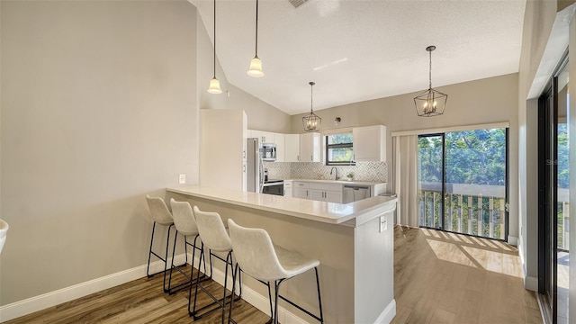 kitchen with white cabinetry, stainless steel appliances, kitchen peninsula, and backsplash