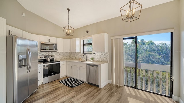 kitchen with sink, white cabinetry, tasteful backsplash, hanging light fixtures, and appliances with stainless steel finishes