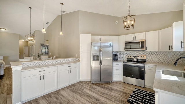 kitchen with pendant lighting, appliances with stainless steel finishes, sink, and white cabinets