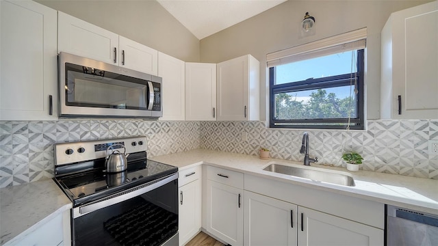 kitchen with stainless steel appliances, white cabinetry, sink, and light stone counters