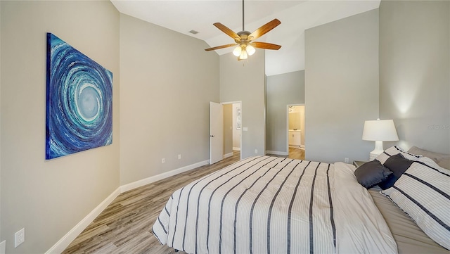 bedroom featuring vaulted ceiling, ensuite bathroom, ceiling fan, and light wood-type flooring