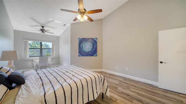 bedroom with hardwood / wood-style flooring, vaulted ceiling, a textured ceiling, and ceiling fan