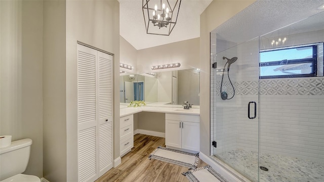 bathroom with vaulted ceiling, a shower with door, hardwood / wood-style floors, and a textured ceiling