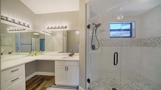 bathroom featuring hardwood / wood-style flooring, vanity, a shower with door, and a textured ceiling