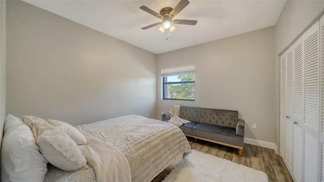 bedroom featuring hardwood / wood-style flooring, a textured ceiling, ceiling fan, and a closet