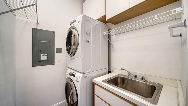 laundry room featuring cabinets, stacked washer and dryer, electric panel, and sink