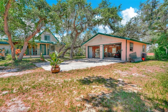 view of front of house with covered porch, an outbuilding, a garage, and a front lawn