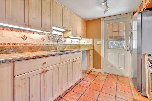 kitchen featuring backsplash, sink, stainless steel fridge, light stone countertops, and light brown cabinetry