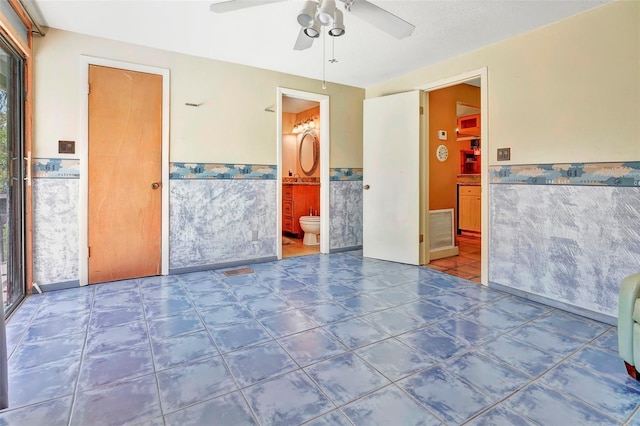 tiled empty room with ceiling fan and tile walls