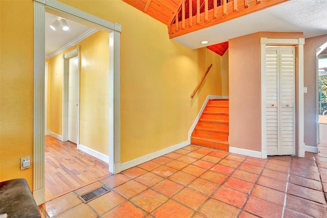 stairs featuring tile patterned floors and crown molding