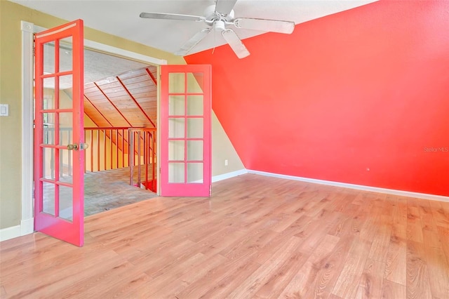 empty room featuring ceiling fan, vaulted ceiling, wood-type flooring, and french doors