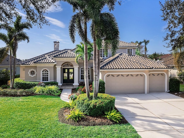 mediterranean / spanish house featuring french doors, a front yard, and a garage