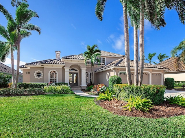 mediterranean / spanish house with french doors, a front lawn, and a garage