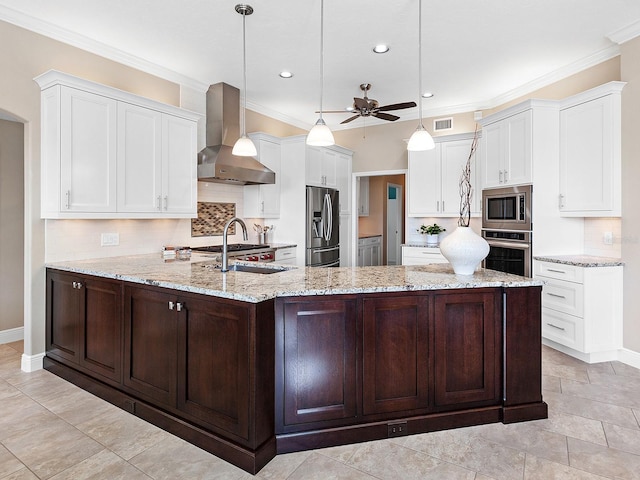 kitchen featuring ceiling fan, hanging light fixtures, wall chimney range hood, a kitchen island with sink, and appliances with stainless steel finishes