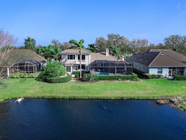 rear view of property with a lanai, a lawn, and a water view