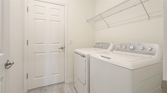 washroom featuring washing machine and clothes dryer and light hardwood / wood-style flooring