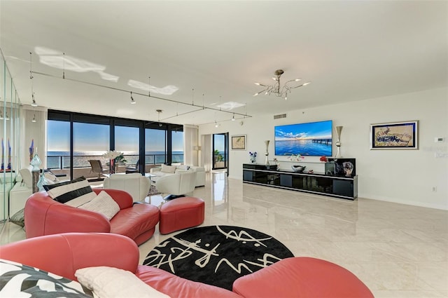 living room featuring floor to ceiling windows, a water view, track lighting, and an inviting chandelier