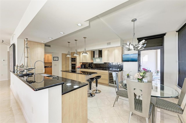 kitchen with light brown cabinets, backsplash, an inviting chandelier, decorative light fixtures, and a kitchen island