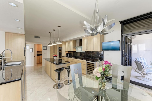 kitchen featuring pendant lighting, wall chimney range hood, sink, wine cooler, and light brown cabinetry