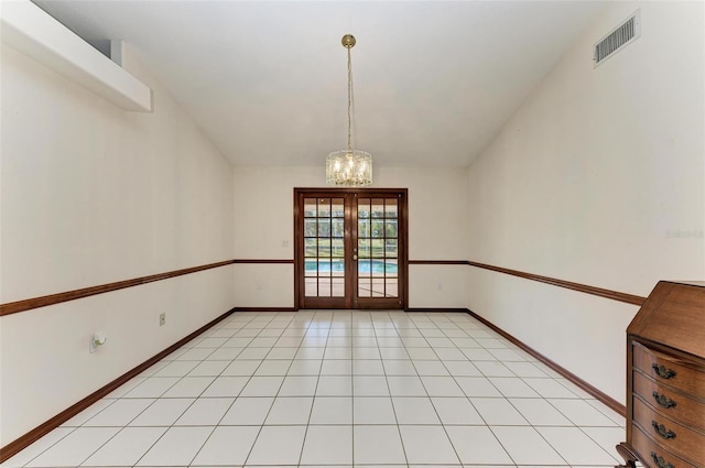 tiled spare room with french doors and a chandelier