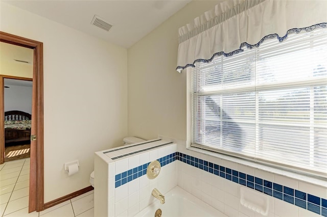 bathroom featuring tile patterned floors, a washtub, and toilet