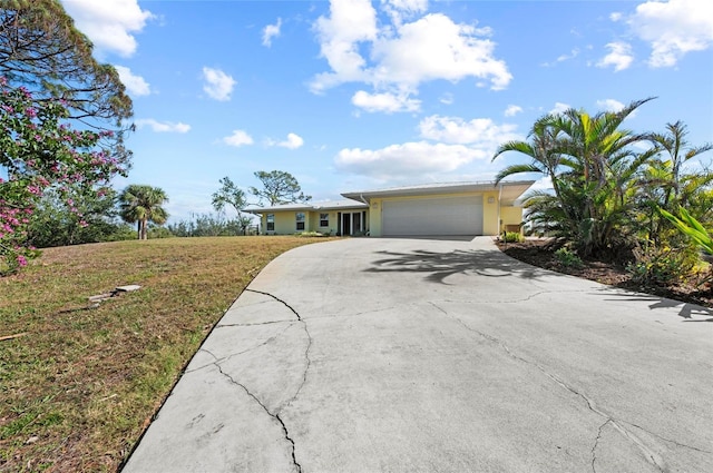 ranch-style house featuring an attached garage, driveway, a front lawn, and stucco siding