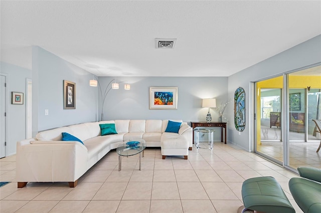 living room featuring a textured ceiling, light tile patterned flooring, and visible vents