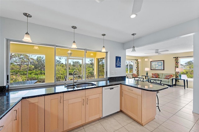 kitchen with hanging light fixtures, white dishwasher, a sink, and a peninsula