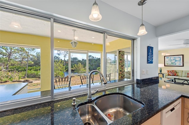 kitchen with dishwasher, hanging light fixtures, dark stone countertops, and a sink