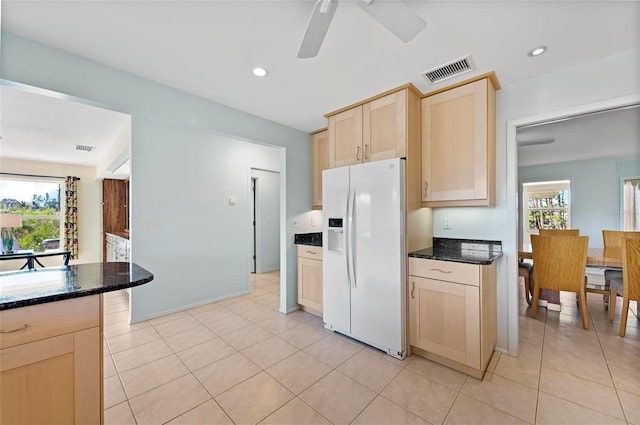 kitchen featuring recessed lighting, visible vents, light brown cabinetry, white fridge with ice dispenser, and dark stone countertops