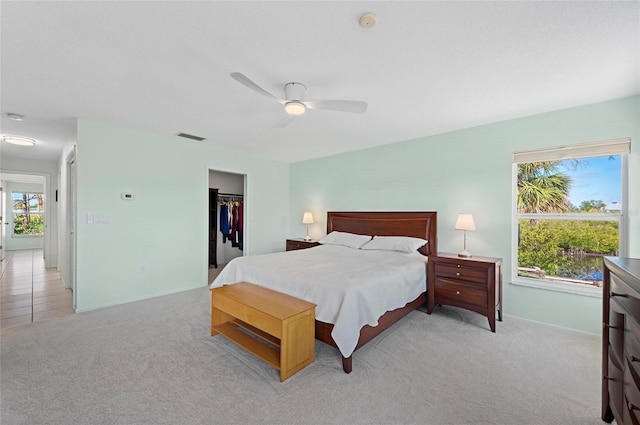 bedroom with a closet, visible vents, light carpet, and multiple windows