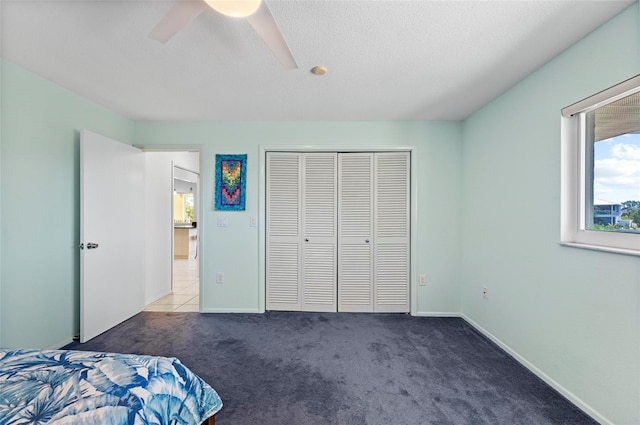 unfurnished bedroom with carpet floors, a closet, a ceiling fan, a textured ceiling, and baseboards