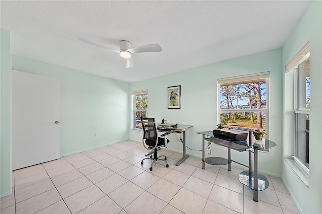 home office with a ceiling fan, light tile patterned flooring, a textured ceiling, and baseboards