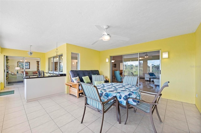 dining area with light tile patterned floors, ceiling fan, and a textured ceiling