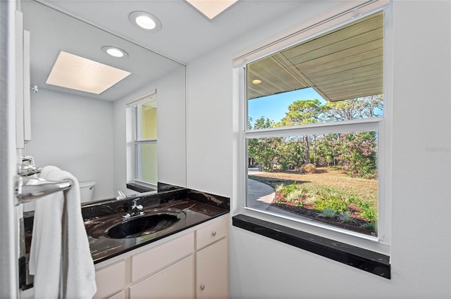 half bath with toilet, plenty of natural light, vanity, and recessed lighting