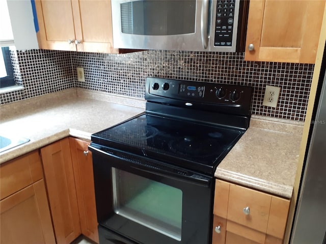 kitchen featuring black range with electric stovetop, fridge, and tasteful backsplash