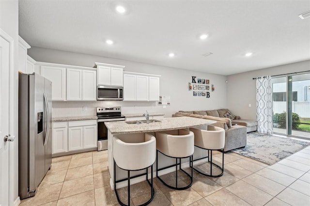 kitchen featuring sink, a breakfast bar area, white cabinets, a kitchen island with sink, and stainless steel appliances