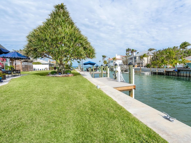 view of dock with a lawn and a water view