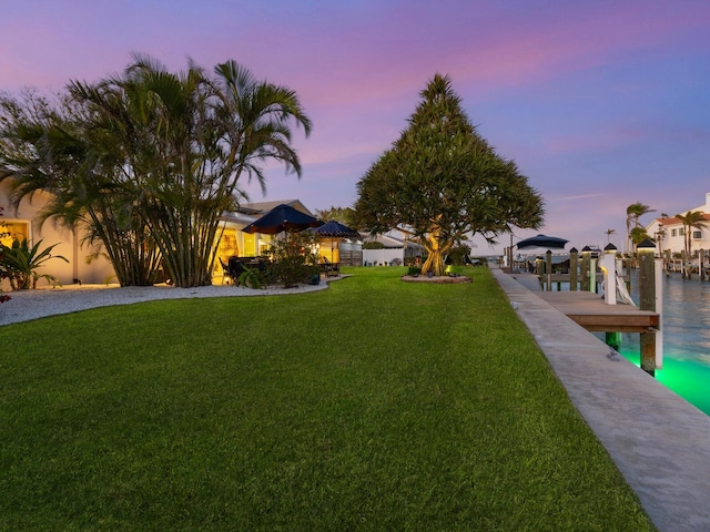 yard at dusk with a water view and a boat dock