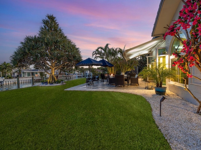 yard at dusk featuring a patio area