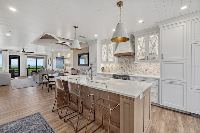 kitchen with ceiling fan, sink, white cabinetry, and a kitchen island with sink