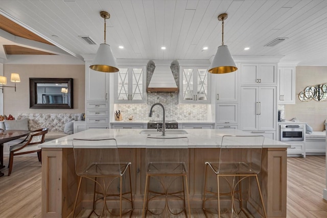 kitchen featuring white cabinetry, a large island, and custom exhaust hood