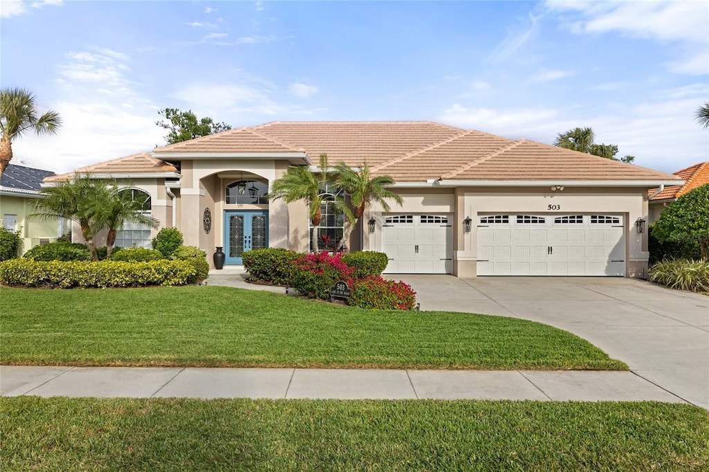 view of front facade with french doors, a front yard, and a garage