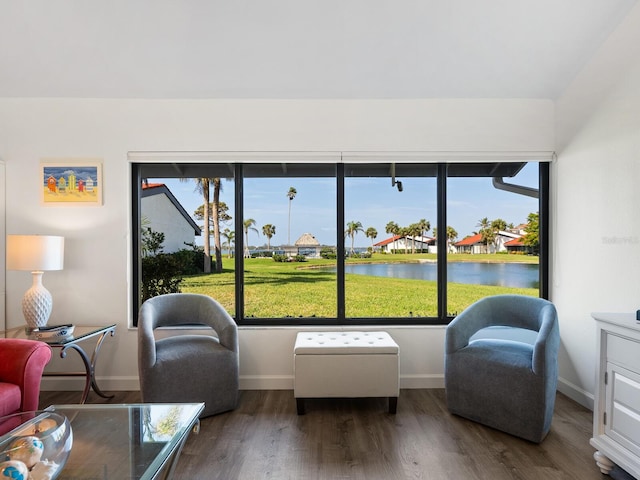 living area with dark wood-type flooring, a healthy amount of sunlight, and a water view