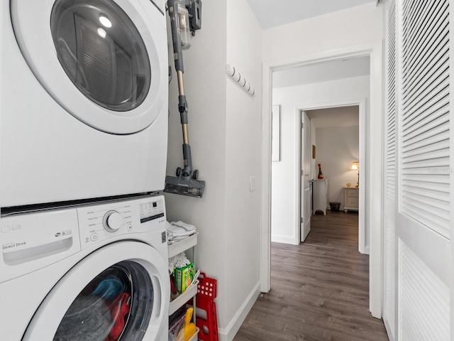 clothes washing area featuring stacked washer and clothes dryer and dark hardwood / wood-style floors