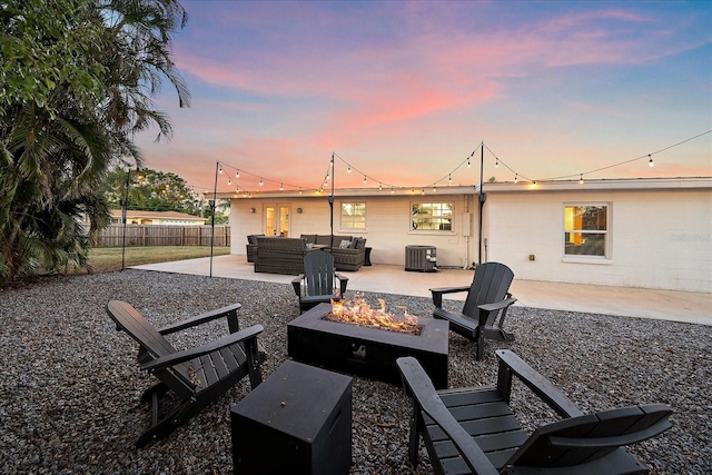 patio terrace at dusk featuring cooling unit and an outdoor living space with a fire pit